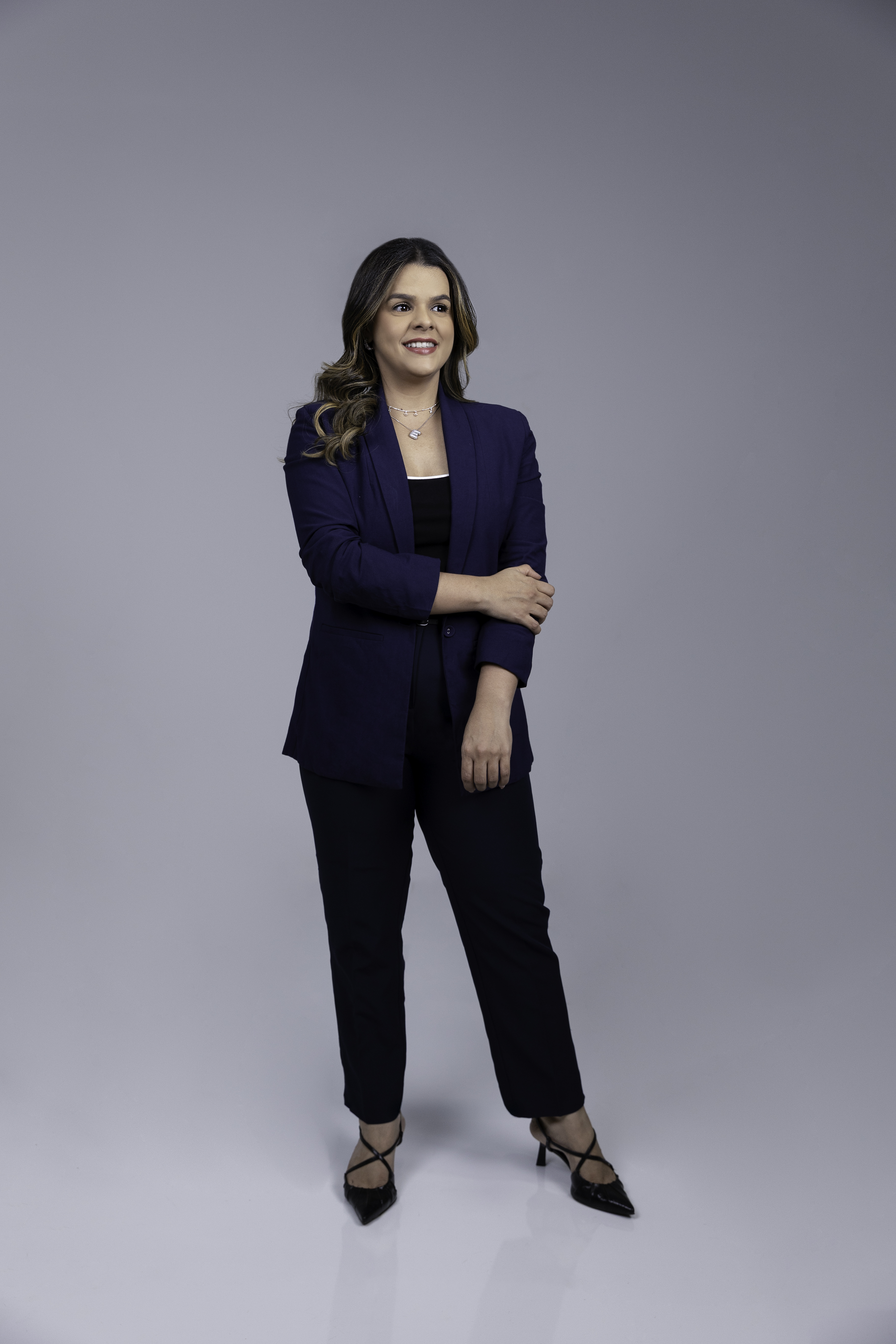 Érica Ferreira de terno azul, em pé e sorrindo